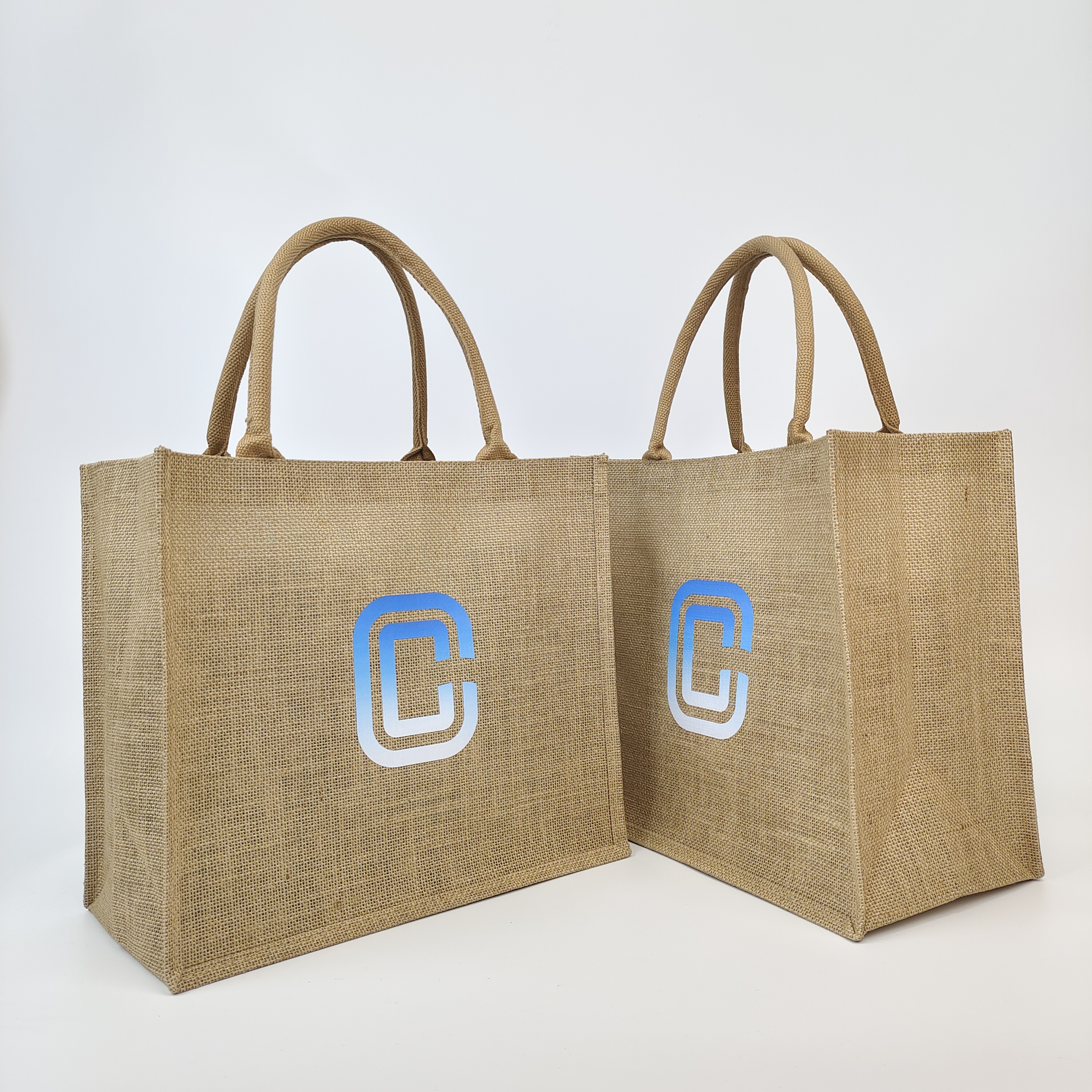 two custom natural jute tote bags with blue and white printed logos and woven handles