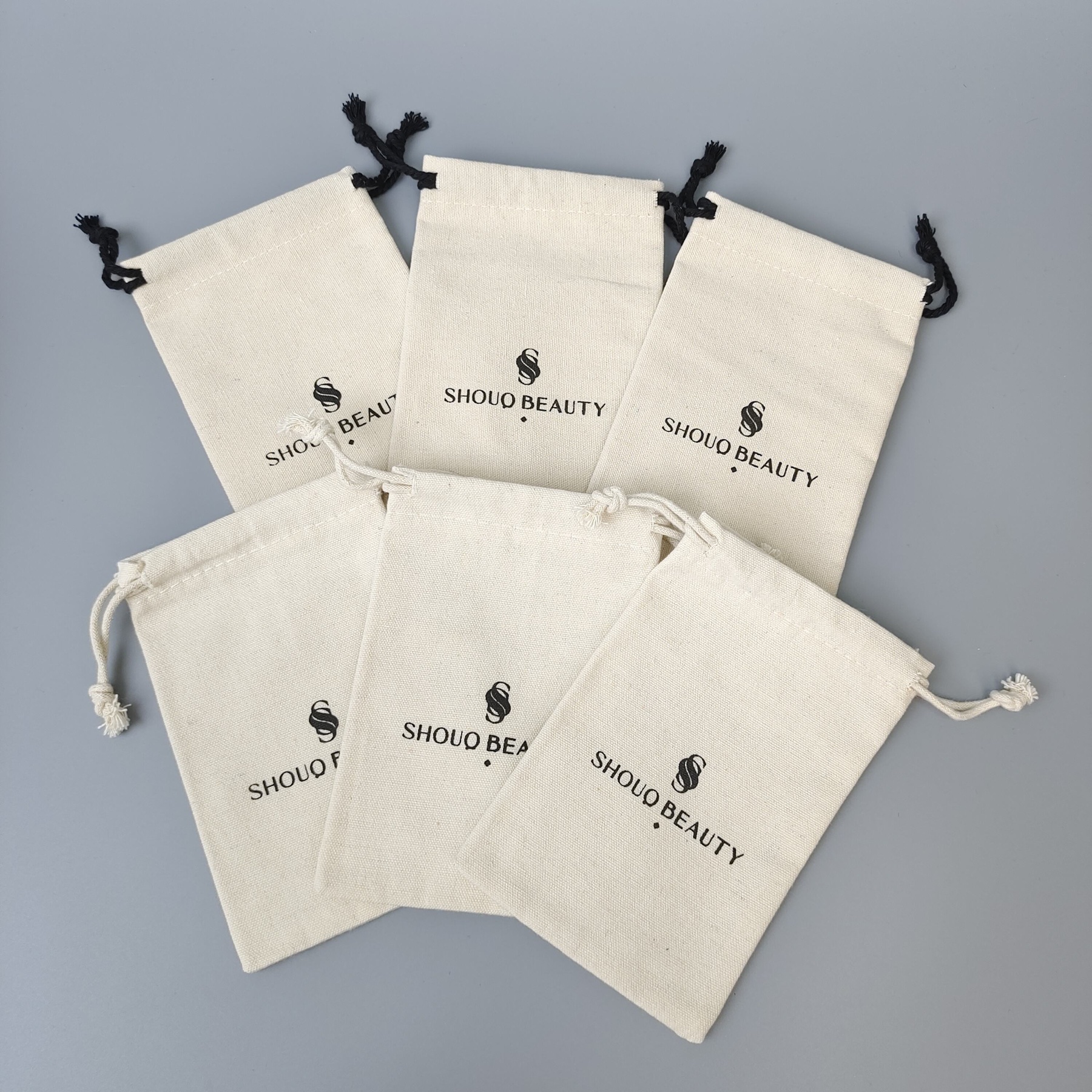 custom cotton drawstring bags in several sizes with printed logos and contrasting cords